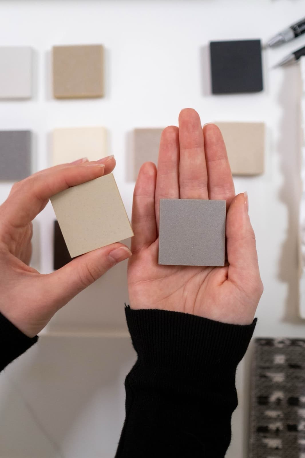 Hands comparing neutral material samples during a design consultation.