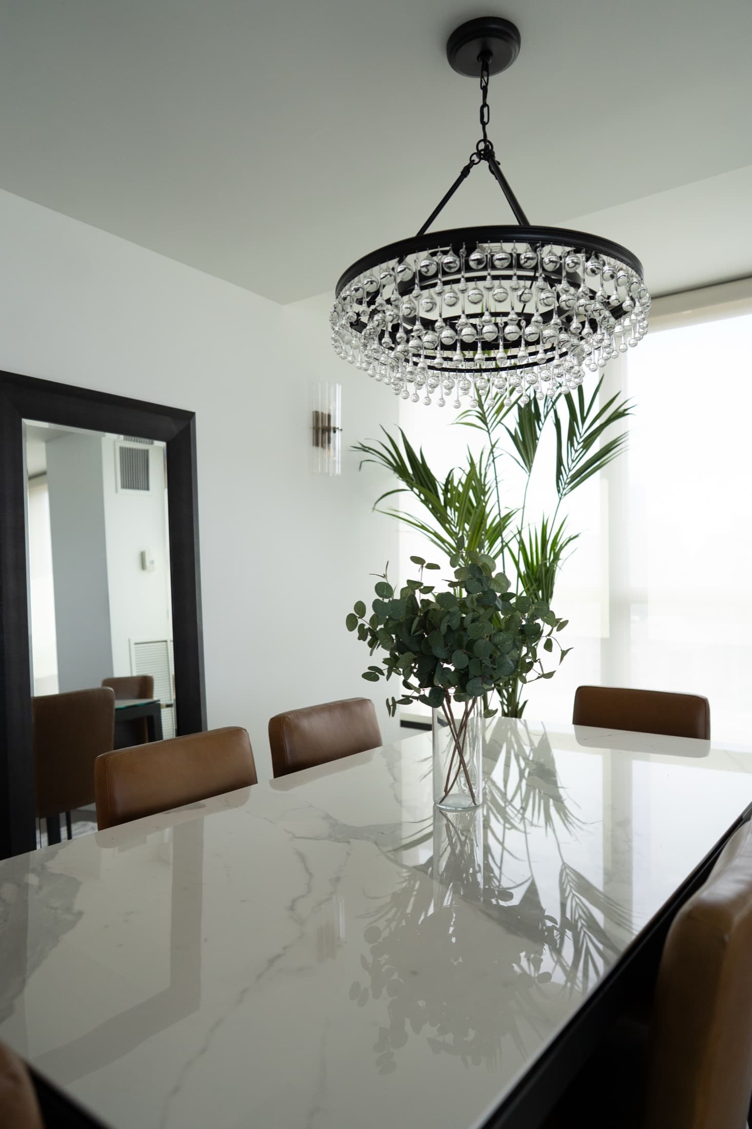 Downtown dining area with a black table, caramel leather chairs, and a crystal orb chandelier.