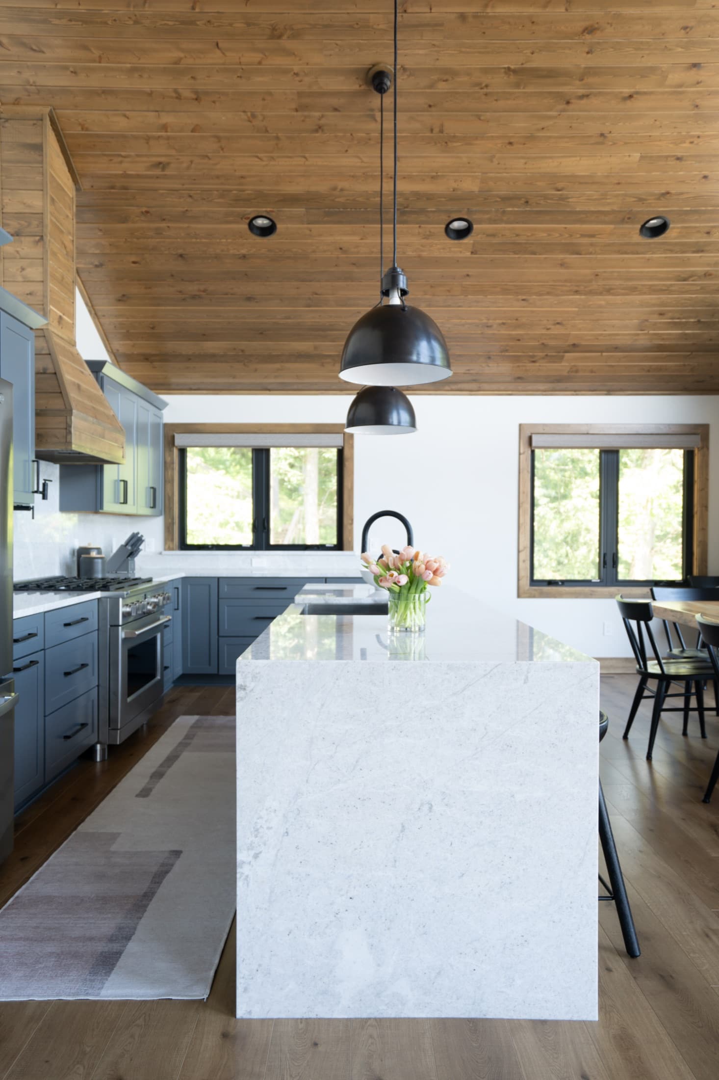 Renovated lake house kitchen with a marble island and slate-blue cabinetry.