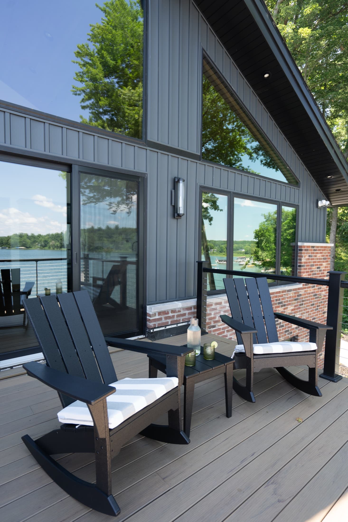 Sunlit lake house living room with a gray sectional opening onto the water.